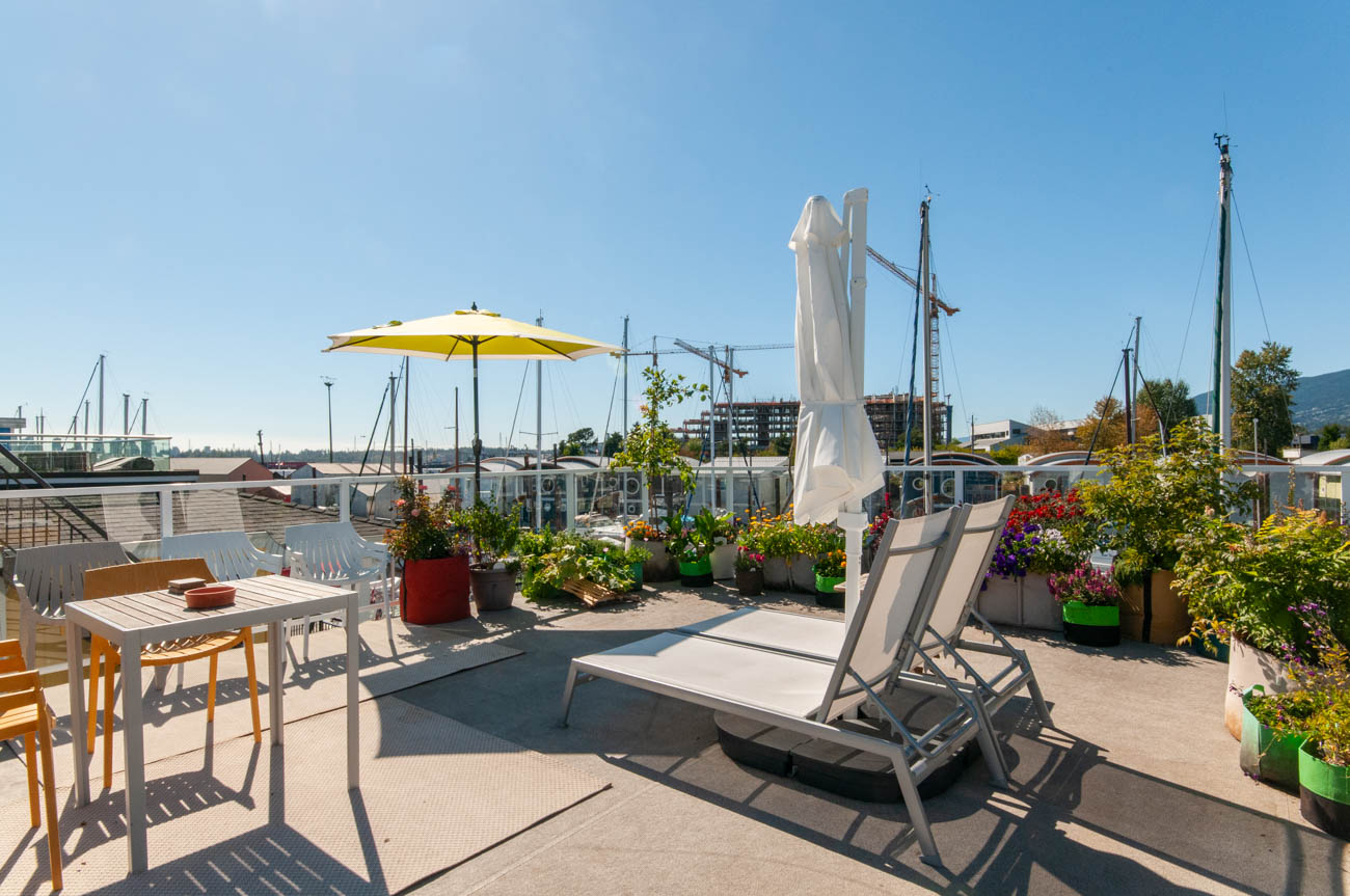 Furnished rooftop patio with lounge chairs, umbrellas, and potted plants. - 415 West Esplanade EFH-10, North Vancouver