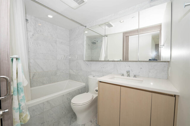Modern bathroom with marble tile walls and light wood vanity cabinetry. - 2204 - 89 Nelson Street, Vancouver Downtown