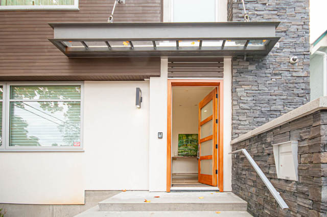 Modern entryway with sleek glass awning and stone staircase leading to a cozy, well-lit interior. - 4504 West 12th Ave, Vancouver West Side