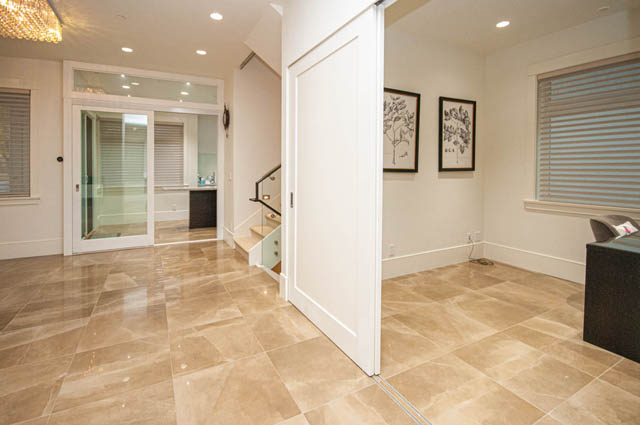 Spacious entryway with glossy tile flooring, glass door, and framed botanical art. - 4504 West 12th Ave, Vancouver West Side