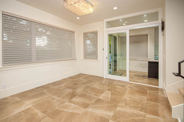 Spacious living room with large windows, tiled floors, and a glass door leading to another room. - 4504 West 12th Ave, Vancouver West Side