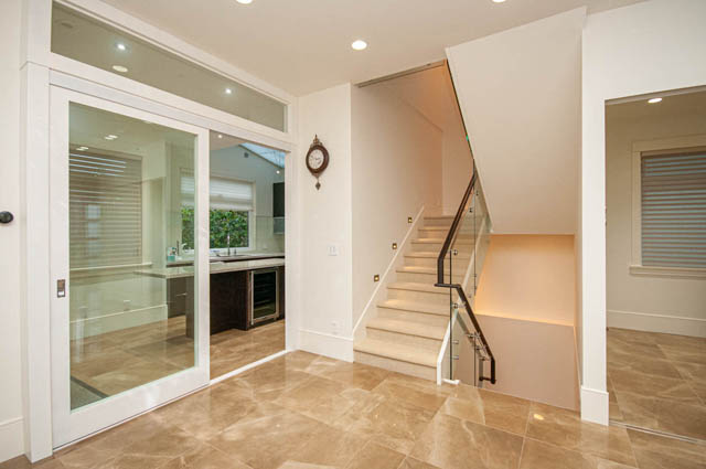 Modern entryway with glass door leading to kitchen, featuring sleek countertops and tiled flooring. - 4504 West 12th Ave, Vancouver West Side