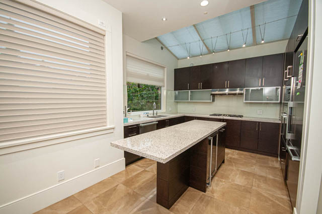 Modern kitchen with granite countertops, dark cabinetry, and a skylight. - 4504 West 12th Ave, Vancouver West Side