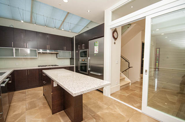 Modern kitchen with granite countertops and stainless steel appliances, showcasing a spacious and well-lit design.