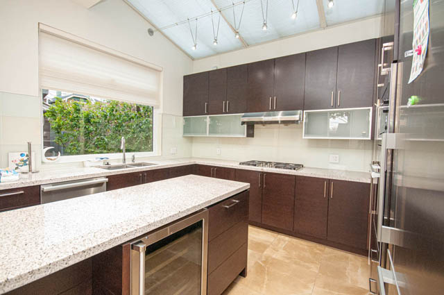 Modern kitchen with granite countertops, dark cabinetry, and a large island. - 4504 West 12th Ave, Vancouver West Side