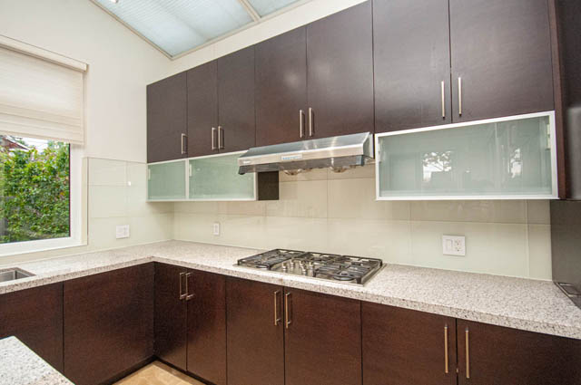 Modern kitchen with granite countertops, dark wood cabinets, and a large window offering a view. - 4504 West 12th Ave, Vancouver West Side