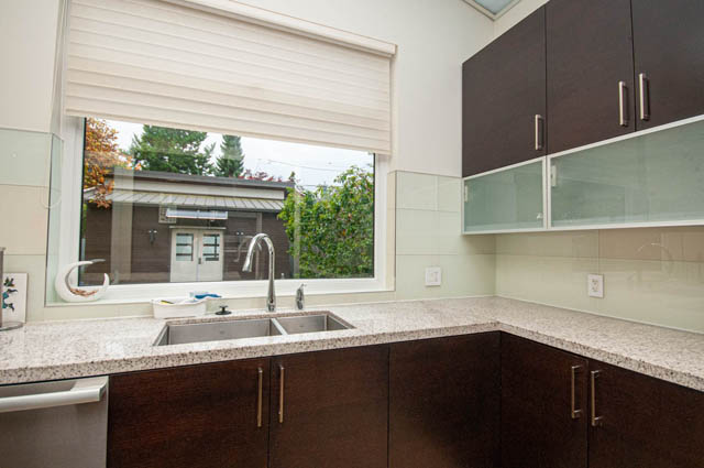 Bright kitchen with granite countertops and modern cabinets, featuring a large window with a city view. - 4504 West 12th Ave, Vancouver West Side