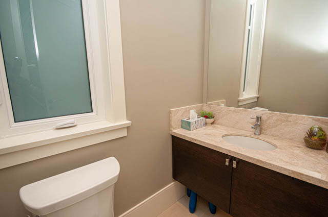 Bathroom with beige countertops, modern sink, and frosted window. - 4504 West 12th Ave, Vancouver West Side