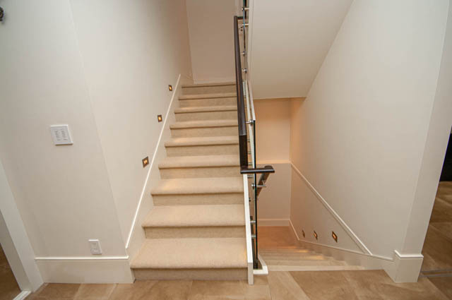 Modern staircase with carpeted steps and sleek railings, leading to upper levels. - 4504 West 12th Ave, Vancouver West Side