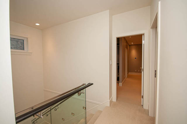 Modern hallway with glass railings and carpeted stairs leading to upper floors. - 4504 West 12th Ave, Vancouver West Side