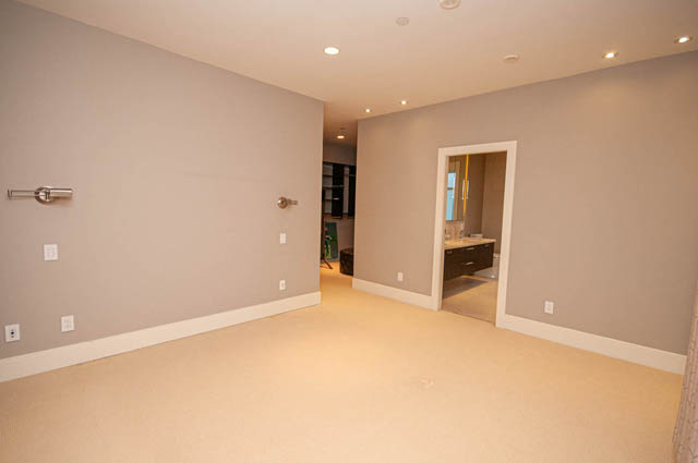 Spacious den with neutral walls, recessed lighting, and a glimpse into a bathroom. - 4504 West 12th Ave, Vancouver West Side