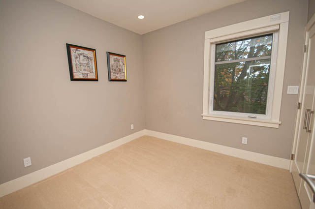 Den with beige carpet, built-in bench, framed artwork, and large window overlooking trees. - 4504 West 12th Ave, Vancouver West Side