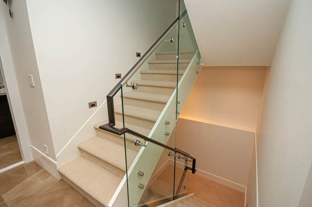 Modern staircase with glass railings and carpeted steps leads to the upper floor. - 4504 West 12th Ave, Vancouver West Side