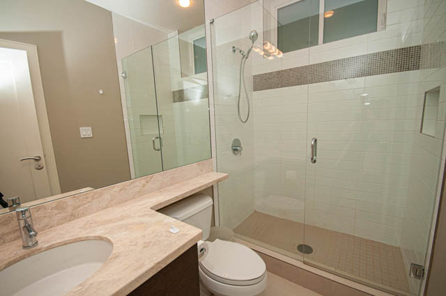 Modern bathroom with marble countertops and a glass shower enclosure. - 4504 West 12th Ave, Vancouver West Side