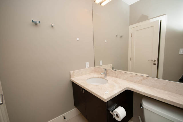Modern bathroom with beige countertop and large mirror, showcasing a sleek design. - 4504 West 12th Ave, Vancouver West Side