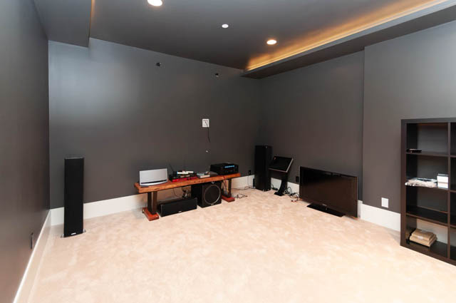 Spacious home theater with wood desk, speakers, and modern lighting. - 4504 West 12th Ave, Vancouver West Side