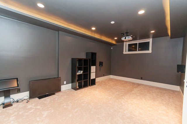 Modern home theater with built-in shelves, recessed lighting, and a sleek projector setup. - 4504 West 12th Ave, Vancouver West Side