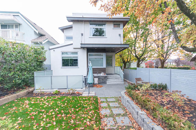 Spacious backyard with stone patio, modern outdoor kitchen, and autumn foliage. - 4504 West 12th Ave, Vancouver West Side