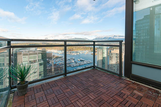 Furnished balcony with wooden deck, city view, and potted plant. - 3102 - 1211 Melville Street, Vancouver Downtown