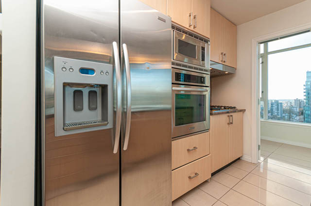 Bright kitchen with stainless steel appliances, city view, and modern cabinetry. - 3102 - 1211 Melville Street, Vancouver Downtown