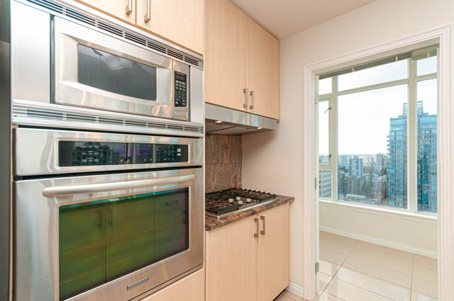 Bright kitchen with stainless steel appliances, hardwood floors, and a city view. - 3102 - 1211 Melville Street, Vancouver Downtown