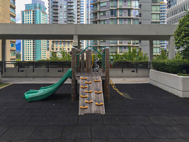 Bright rooftop playground with slide and climbing structure, city views in background. - 3102 - 1211 Melville Street, Vancouver Downtown