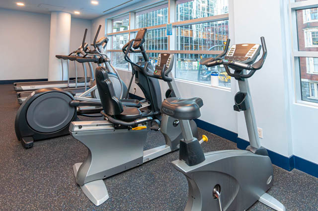Bright fitness room with cardio equipment and large windows. - 3102 - 1211 Melville Street, Vancouver Downtown