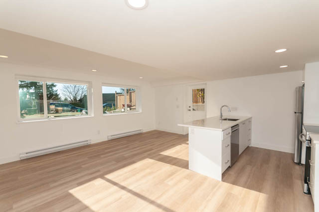 Bright kitchen with white cabinetry and hardwood floors, featuring a large island and a skylight. - Suite - 778 Crystal Court, North Vancouver