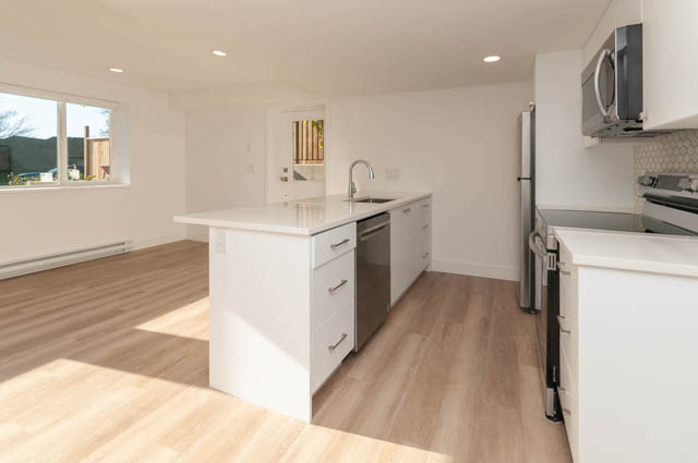 Bright kitchen with white cabinetry, hardwood floors, and a large island. - Suite - 778 Crystal Court, North Vancouver