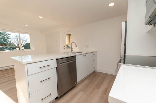 Bright kitchen with white cabinets, stainless steel appliances, and hardwood floors. - Suite - 778 Crystal Court, North Vancouver