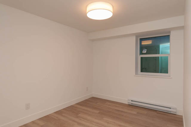 Spacious bedroom with hardwood floors and a window, ready for furnishings. - Suite - 778 Crystal Court, North Vancouver