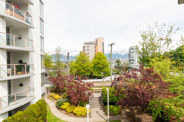 Bright living room with city view and vibrant garden. - 107 - 1633 8th Ave W, Vancouver West Side