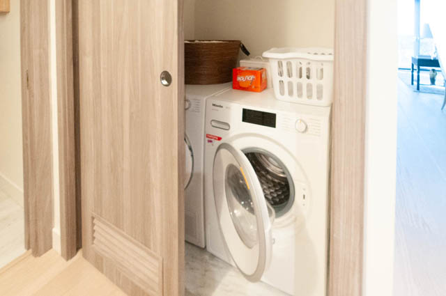 Compact laundry room with wooden cabinets and a Miele washer. - 2818  - 89 Nelson Street, Vancouver Downtown