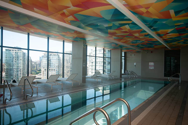 Spacious penthouse with vibrant, colorful ceiling, large windows offering stunning city views, and a luxurious indoor...