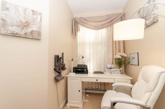 Spacious home office with white desk, modern chair, and floral artwork, perfect for work or relaxation. - 102-1633 Mackay Avenue, North Vancouver