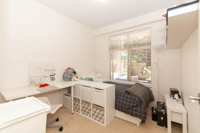 Bright bedroom with white furniture, neatly made beds, and a desk with a chair. - 102-1633 Mackay Avenue, North Vancouver