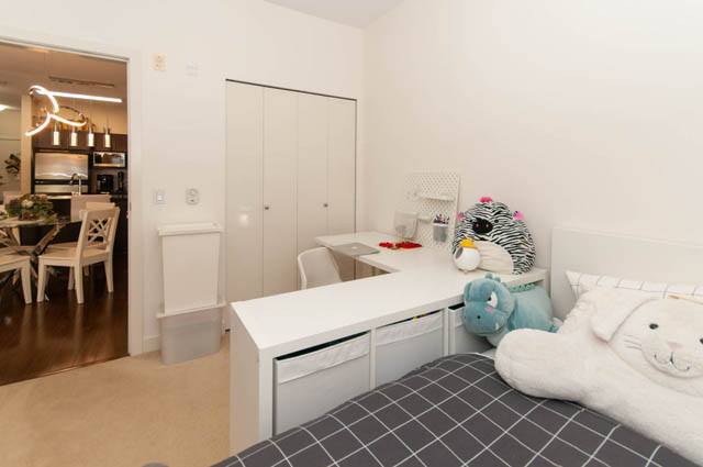 Spacious bedroom with modern desk, plush toys, and hardwood floors. - 102-1633 Mackay Avenue, North Vancouver