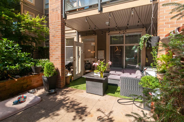 Furnished patio with cozy seating, string lights, and lush greenery. - 102-1633 Mackay Avenue, North Vancouver