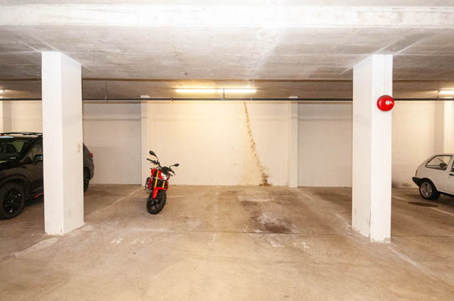 Spacious garage with concrete pillars and a red motorcycle. - 102-1633 Mackay Avenue, North Vancouver