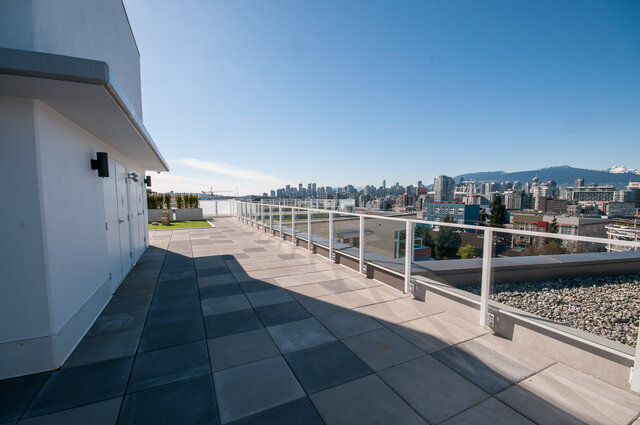 The balcony has tiled flooring, white railings, and a city skyline view. - 212-311 East 6th Avenue, Vancouver East Side
