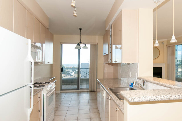 Bright kitchen with granite countertops and city view through sliding doors. - 607-160 E 13th Street, North Vancouver