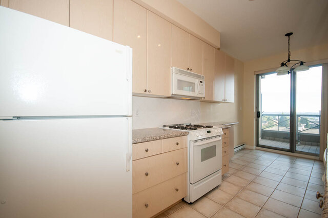 Bright kitchen with white appliances and granite countertops, tile flooring. - 607-160 E 13th Street, North Vancouver