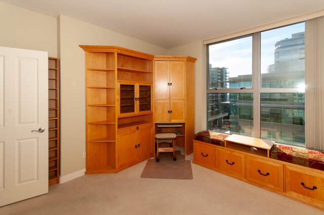 Cozy bedroom with wooden built-in storage and city view through large windows. - 607-160 E 13th Street, North Vancouver