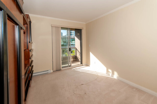 Bright bedroom with sliding glass doors and city view through balcony. - 607-160 E 13th Street, North Vancouver