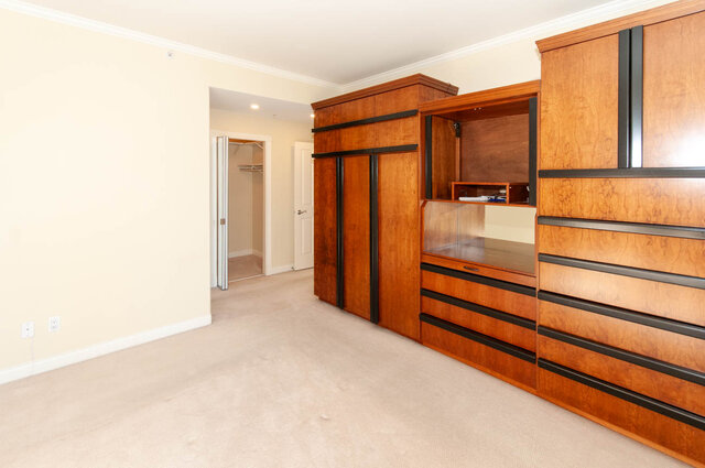 Spacious bedroom with custom wooden wardrobe and beige carpet flooring. - 607-160 E 13th Street, North Vancouver