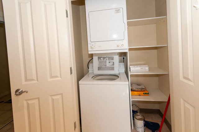 Laundry room with stacked washer-dryer and built-in shelves. - 607-160 E 13th Street, North Vancouver