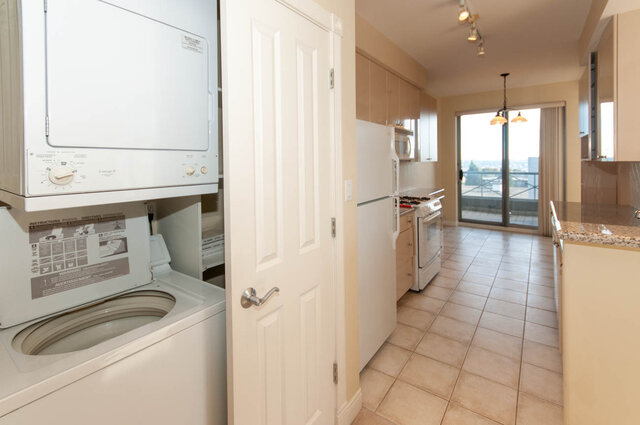Laundry area with stacked white washer/dryer and tiled flooring. - 607-160 E 13th Street, North Vancouver