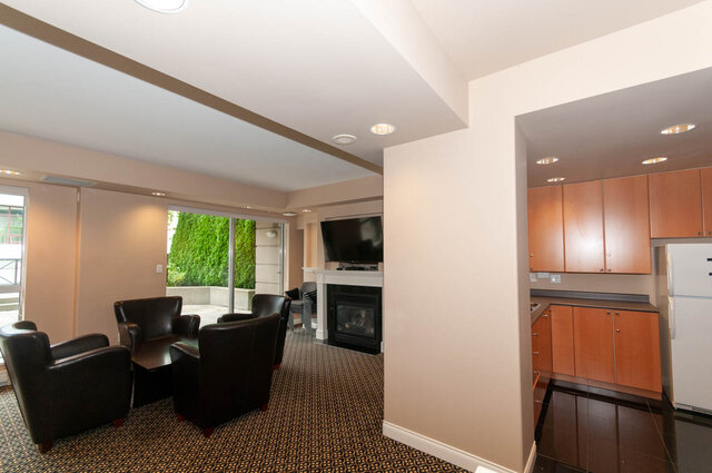 Open-concept living space with black leather chairs and wooden cabinetry. - 607-160 E 13th Street, North Vancouver