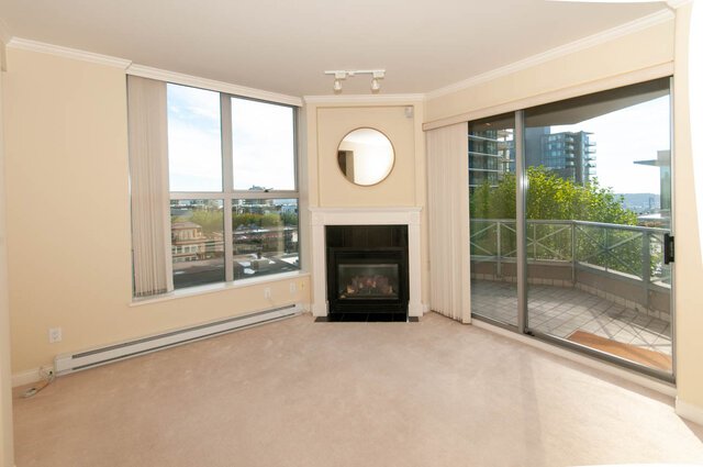 Bright living room with city views through large windows and a fireplace. - 607-160 E 13th Street, North Vancouver