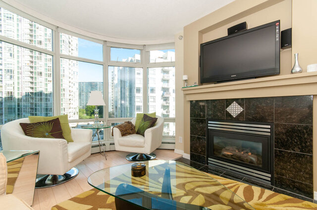Spacious living room with large windows, modern furniture, and a city view. - 905 - 1199 Marinaside Cres., Vancouver Downtown